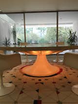 The illuminated base of the circular 96-inch marble dining table is believed to be the inspiration for Eero Saarinen's Tulip Chair designed in 1956. A brass pump in concealed in the base, which delivers water to the center basin of the table, where Xenia Miller liked to float flowers as a centerpiece. Initially the table was complemented by wire-based Eiffel Tower Chairs by Charles Eames. Saarinen later replaced them with the more subdued tulip chairs. The covers feature needlepoint designed by Girard and created by Xenia Miller's friends. #Girard #AlexanderGirard #Saarinen #Eames #dining #table #MillerHouse #midcentury