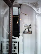 Carefully placed modern touches illuminate restored details in the home. An industrial-style pendant, which Jeff and Jason created themselves using a DIY instructional kit by lighting designer Lindsey Adelman, hangs from the intricate millwork in the entryway. The print is by photographer Anna Wolf.
