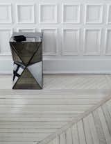 In the downstairs den, the mirrors facets of a West Elm side table refract the linearity of the moulding and hardwood flooring. Removing dated carpeting and vinyl tiles throughout, the couple unearthed and preserved the original wood floor, then sanded, twice bleached, whitewashed, and sealed it to achieve a neutral gray finish.