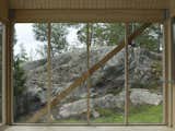 A simple timber frame and wide expanses of glass enhance the structure's connection to Viggsö's varied terrain, marked by rocky cliffs, wild-bent pine trees, heather, and lichen.