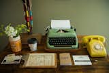 A working vintage typewriter and telephone top the antique desk.