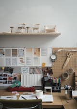 A shelf of models sits over a design station layered with inspiration.&nbsp;