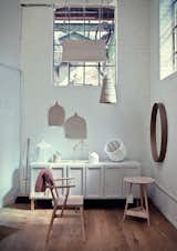 In the Pinch showroom, a Holland Park School armchair designed by Richard Pinch for Ercol sits beside a Clyde lamp table and Frey sideboard from the Pinch collection. The brand's Iona mirror hangs on the wall while their gauzy Beata pendant dangles from above.