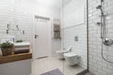 Bath Room, Ceramic Tile Floor, Vessel Sink, Full Shower, Wood Counter, Subway Tile Wall, and One Piece Toilet Subway tile, another fixture of the urban landscape, envelops the bathroom.  Photo 9 of 42 in lightness by Jessica Parsons from Rarely Do Family Homes 
Look So Raw