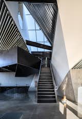The faceted corrugated metal ceiling opens up over the staircase, soaring to a height of 32 feet above the ground floor. Like much of the metalwork, the steel staircase and railing were fabricated by Tutto Ferro.