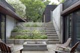 A stepped concrete garden planted with herbs and flowers marks the descent to the house. The courtyard is the focal point of the U-shaped structure; there is clear visibility between the kitchen on one side and the children's bedrooms on the other.  Kristina Staneva’s Saves from House of the Week: A Striking Slope