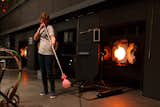 Using an elongated rod, the glassmaker blows air into the vessel to further shape and complete the form of the head.