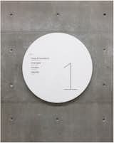 Identification and wayfinding signage appears on shiny metal discs that stand in contrast to the building's textured concrete walls.