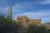 Three pavilions of masonry, rusted steel, and glass come together in Tucson, Arizona, to create a home designed by Ibarra Rosano Design Architects that draws inspiration from the desert landscape. Each facade is in direct response to the sun, wind, topography, vegetation, and views. Windows are long and shaded, entryways are covered, and views are curated to capture indirect sunlight and provide vistas of the landscape beyond.