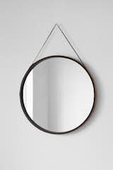 Leather Wrapped Mirror is a minimal mirror created by Australia-based designers Owen Architecture. The circular mirror features a rope attached on either end to allow the mirror to be hung. The outer perimeter of the mirror is constructed of natural cowhide leather with black waxed linen threading. The inside of the mirror’s frame contrasts against the natural hide, creating a focus toward the reflection of the mirror.