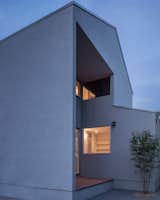 House in Arayashiki is a minimal home located in Saga, Japan, designed by Yabashi Architect & Associates. The two-story wooden home is situated in a quiet residential neighborhood, and features a monolith facade with large windows that peer through to the other side of the building. A small terrace is accessible via sliding glazed doors that transition into the backyard.