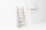 The Belt Series is a minimal collection of objects by Munich-based designer Jessica Nebel, inspired by the language of traditional leather crafts. Combining wood with leather creates a highly functional characteristic and beautiful aesthetic. To be installed, the hanging rack only uses two screws and when not in use, it folds up against the wall. The ladder serves as a shelf or shoe rack. The set-up consists of a typical ladder structure with additional horizontal bars that are held by leather belts.