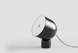 Faro is a minimalist table lamp created by Valencia-based designer LaSelva. It is divided in two parts, the base and the lampshade without the use of any hardware. The cylindrical marble base has a magnet at the top, surrounded with a thin felt, to allow the shade to stay in the desired position. The lamp shade can rotate 360º in horizontal and 45º in vertical keeping the base in the same spot. The spherical shape of the shade makes it possible for it to pivot from the base adopting various positions. The shade is closed with a translucent polypropylene. The metal shade finishes include black matte, black chrome, and antique brass.