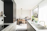 Project BK is a minimal residence located in Afsnee, Belgium, designed by JUMA Architects. For the internal conversion of a farm in rural Afsnee, JUMA sought to strike a balance between the authentic elements of the house and a newly designed contemporary interior. In the old situation, the large open spaces were last used as offices. JUMA transformed them into a logical sequence of warmly furnished living areas. The original entrance, for instance, was moved, and those entering the farm now enter near the central staircase that connects the ground floor with the first floor. To preserve the spaciousness of the room, black-stained vertical wooden slats were placed behind a natural stone drawer unit, designed to portion off the space between entrance and office. The raised dark polished concrete floor that extends to the office reinforces this division.