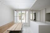 Renovation House V is a minimal home located in Antwerp, Belgium, designed by Hans Verstuyft Architecten. The space is characterized by the use of raw materials, mostly concrete, mixed with the warmth of natural wood. An array of planks are used for the ceiling within the kitchen to create depth, and filter natural light from above. A custom-built wooden bench maximizes the wall space, matching the grain from the dining table.