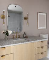 A guest bathroom is awash in blush for a lighter departure from the other, featuring a Concrete Collaborative countertop and hardware and sconces from Park Studio LA.&nbsp;