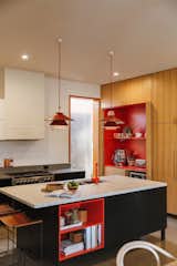 The owners asked for "random pops of red" to flash throughout their kitchen renovation, complete with blackbutt wood, concrete countertops, and a terrazzo island.