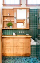 Green tiles complement an oversized vanity in the bathroom, which gets lot of natural light.