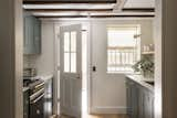 Kitchen, Marble Counter, Medium Hardwood Floor, Colorful Cabinet, and Range The marble countertops and gold hardware are a subtle nod to the past, while also fitting into today's trends.  Photos from Before & After: A 19th-Century Townhouse in Brooklyn Is Exquisitely Restored