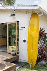An outdoor shower is right off the kitchen, next to a surfboard made by Kurtis Woodin. The fiberglass and wood windows and doors are from Marvin.