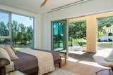 Bedroom, Bed, Ceiling Lighting, Light Hardwood Floor, and Chair A bedroom looks out over the pond, and has an accompanying deck.  Photo 3 of 8 in Bedrooms by Shelly Baker from A Couple Carve Open a Working Sonoma Farmhouse to Savor the Surrounding Fields