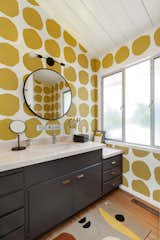 In another bathroom, a polka dot wallpaper print creates a playful atmosphere while the dark-toned vanity adds a more serious contrast.