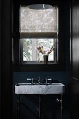 Friday wanted to make the powder room distinctive, and she chose a navy lime wash paint from Color Atelier to do so. A Stone Forrest marble vanity and Highgate Waterworks faucet sit under a vintage pendant.