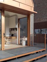 Outdoor, Back Yard, Metal Patio, Porch, Deck, Metal Fences, Wall, Wood Patio, Porch, Deck, and Small Patio, Porch, Deck A small workspace is tucked into the far wall of the unit, with additional storage.  Photos from Cosmic Buildings’s $279K Tiny Home Recycles Water and Generates Its Own Solar Power