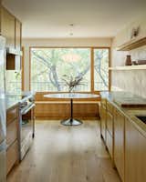 An Aria table from Room and Board creates a spot to gather. The countertop is Barbados honed marble from Walker Zanger, and it surrounds an LG induction cooktop.