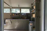 A refrigerator and freezer are integrated into the cabinetry, concealed behind storage hooks on the far left. The far right cabinet is equipped with a mobile induction hob for cooking.