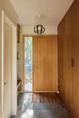 The new entrance was moved toward the south of the house to create a larger kitchen and bathroom and place all of the private spaces toward the south. Zander came up with the idea to place a litter box and fan within the custom cherry millwork. A T.M. Cobb front door and Zia terrazzo tile in Alexander surround it.