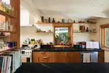 Soapstone countertops were installed above custom cherry millwork in the expanded kitchen, which has enough shelving for the couple's ceramics collection.