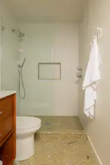 The renovated bathroom replaced the former bathtub with a walk-in shower. The floor is by Concrete Collaborative, which is beneath a West Elm vanity.