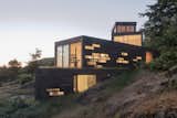 From below, the volumes seem to cascade down the hillside. Windows light up in a dramatic pattern at night, a sharp contrast to their subtle shapes during the day.