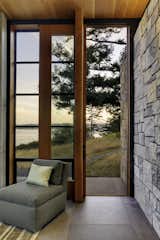 Glass window-walls contrast with the adjoining stone wall.
