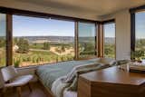 The foot of a custom bedframe sits flush against the wall and large operable window.