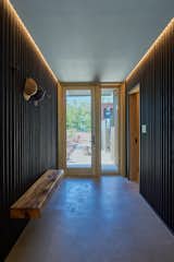 Black painted corrugated metal and recessed cove lighting emphasize the hallway axis of the home.