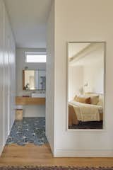Dandelion cement tiles by Marrakech Design adorn the floor of the primary bathroom. The wall tile is from Daltile. The bed, seen in the mirror at right, is by Industry West.