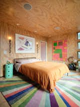 A rug by Momeni Delhi strikes a colorful note in the primary bedroom, which features Project Room sconces and a Kartell Componibili storage unit. The artworks are by Yrjo Edelmann (left) and John Finneran. 