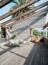 Tongue-and-groove cypress clads the house as well as the rear deck, which is a favorite gathering spot for parties and the couple’s annual "Fakesgiving" dinner. Chairs by Mexa Design for CB2 surround a Project Room table. 