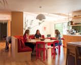 The kitchen now features a seating area featuring a Moooi Container table, Hay chairs and a banquette upholstered in a crimson fabric by Kvadrat. The pendant is by &amp;Tradition.