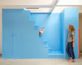 Gus, the family’s Scottish Fold cat, perches on the stair to the kids’ lounge. Painted in Benjamin Moore’s True Blue, it also holds bonus storage for the ADU.