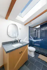 A Brazilian slate tile floor is paired with blue ceramic shower tile by Linea Gloss in one of the new upstairs bathrooms.