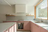 In the kitchen, rose pink cabinetry combines with counters by Surface1 in a pearl gray. The cooktop and oven are by Bosch, and the faucet is by Graff.