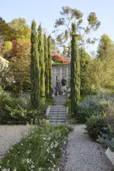 In the upper garden, Ruth and Scott walk down the stairs leading to a spot that once featured a long, narrow pool. "I was never going to fill it with water because I didn’t see it as practical or safe," says Scott. "I decided to change it into a planting area." Johnston Vidal assisted Terremoto principal Jenny Jones on the build-out of the landscape, in addition to overseeing the hardscape and pool design.