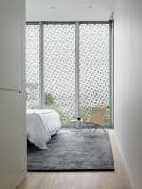 The master bedroom, modest in size, features a Stark area rug and a wicker PK22 chair by Poul Kjærholm for Fritz Hansen.