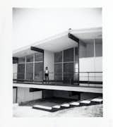 DeLeeuw Residence black and white historic photo of mid century home exterior with person standing on upper level patio.