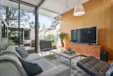 The inviting living room's floor to ceiling windows and glass doors open up to the courtyard for optimal indoor-outdoor living.
