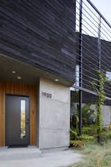 Both privacy screen and modern trellis, the slatted steel frame continues the angled geometry of the facade, extending the plane of the entrance and carport to the corner of the home. Concrete and clear-coated cedar slats complete the facade, and aluminum Ridge house numbers by Hsiaolin Chi for NakNak adorn the home's entrance.