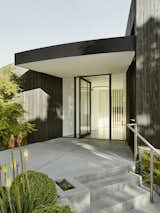 Continuing the progression, an ascent past a green wall and other layered plantings brings residents and visitors to the front entry, where the Fleetwood pivot door invites first glimpses into the home.